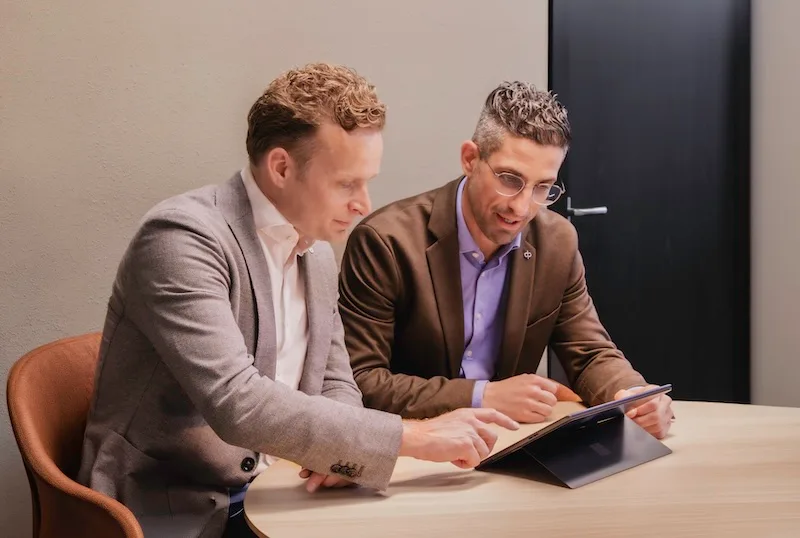 Twee professionals in overleg op een foto van Onderwijs in Business